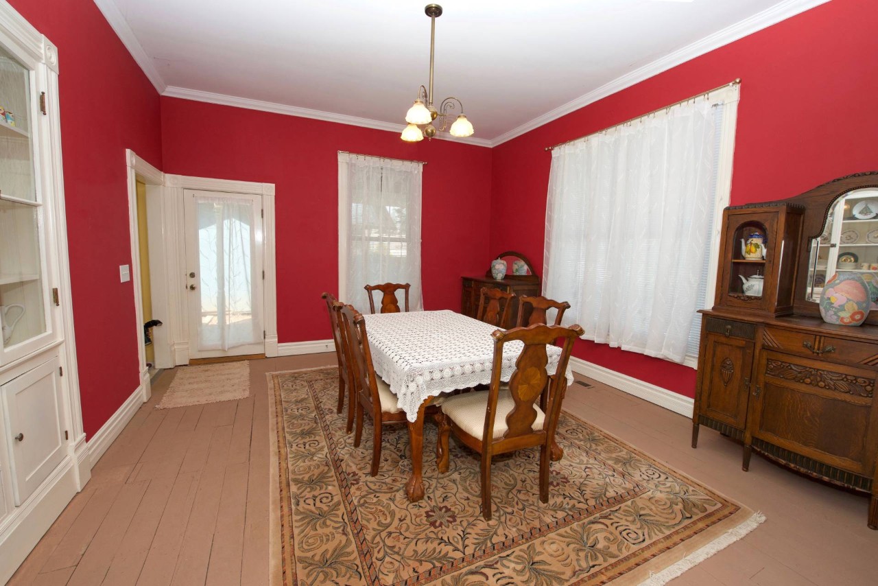 A dining room with soft window treatments and red walls at The Shade Shop Maine near Kennebunk, Maine(ME)